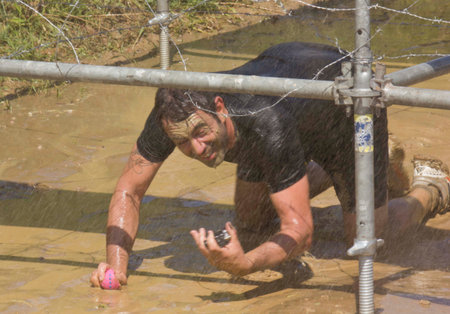 SIGNA, ITALY - MAY 9 2015: Man passing under the wires in a mud ground during a mudrun competition...