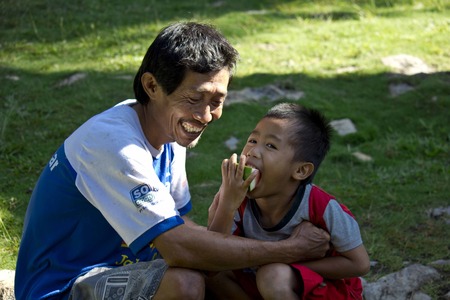 TANA TORAJA, INDONESIA - JULY 4 2012: Young boy  and his dad smiling while eating watermelon in a Torajan villageのeditorial素材