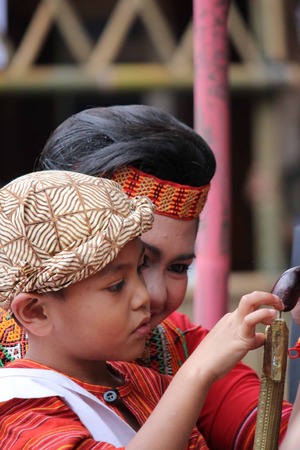 TANA TORAJA, INDONESIA - JULY 3 2012: Young Indonesian boy playing with his sister during a ceremony in Tana Toraja, Indonesia, traditionally dressedのeditorial素材