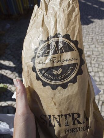 SINTRA, PORTUGAL - OCTOBER 25 2014: A Paderia Bakery bag in Sintra, Portugal, for the traditional Portuguese sweet Pastel de Nata, in a  human handのeditorial素材