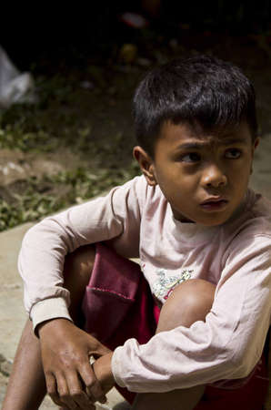 TANA TORAJA, INDONESIA - JULY 3 2012: Portrait of a young Indonesian boy sit on the streetのeditorial素材