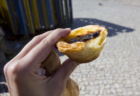 Human han hanging a bite Pastel De Nata, Traditional Portuguese sweet, in Sintra, Portugalの写真素材