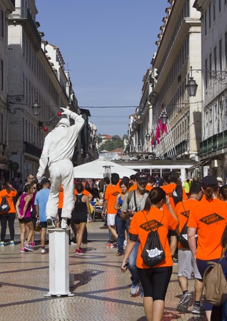 LISBON, PORTUGAL - OCTOBER 26 2014: Participant at Lisbon marathon walking in Rua Augusta after the competition, with a street performer in the middleのeditorial素材