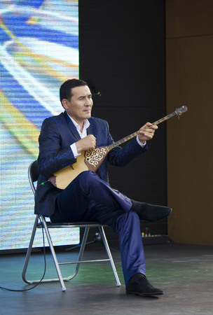 MILAN, ITALY - JUNE 29 2015: Man playing a Dombra, the most popular traditional musical instrument of Kazakhstan, at Expo 2015 in Milan, on June 29 2015のeditorial素材