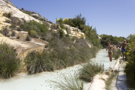 BAGNO VIGNONI, ITALY - JUNE 3 2017: People bathing in the free area of Bagno Vignoni in Tuscany, Italy, free accessible hot springs puddle trough vegetationのeditorial素材