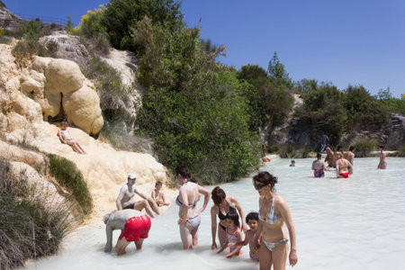 BAGNO VIGNONI, ITALY - JUNE 3 2017: People bathing in the free area of Bagno Vignoni in Tuscany, Italy, free accessible hot springs puddle trough vegetationのeditorial素材