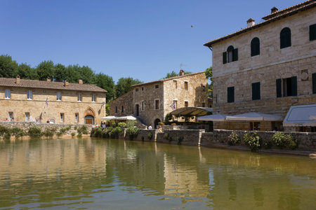 BAGNO VIGNONI, ITALY - JUNE 3 2017: Piazza delle sorgenti medieval square in Bagno Vignoni, with a lake of hot spring water and people looking at itのeditorial素材