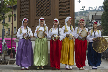 SARAJEVO, BOSNIA AND HERZEGOVINA - AUGUST 20 2017: Group of traditional dressed bosnian girls in front of Sebilj fountain, holding tambourinesのeditorial素材