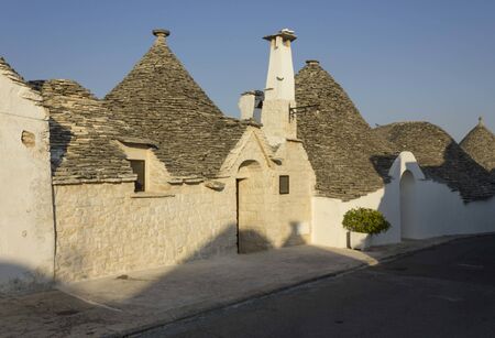ALBEROBELLO, ITALY - AUGUST 27 2017: View at sunset light of traditional row of trullo housesの写真素材