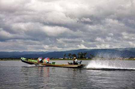 coloured umbrellas on typical wooden Myanmar boat, Inle lakeの写真素材