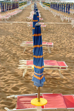 line of closed blue umbrellas on the beachの写真素材