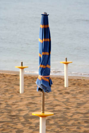 one closed blue umbrella on the beachの写真素材