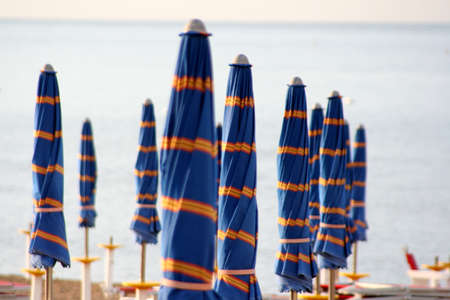 closed blue umbrellas on the beachの写真素材