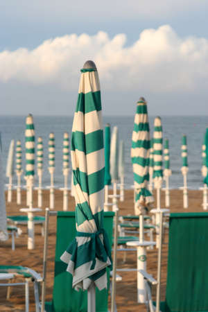closed umbrellas and chairs on the beachの写真素材
