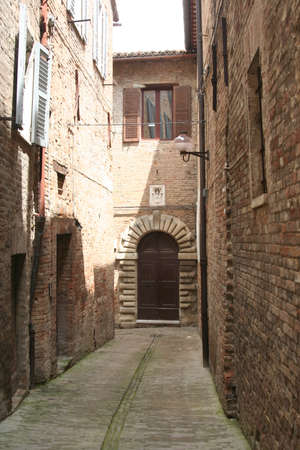 Small road with red bricks houses in downtown Urbino, central Italyの写真素材