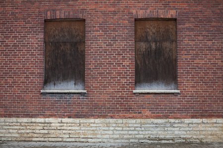 Windows closed shut on a dark red brick houseの写真素材