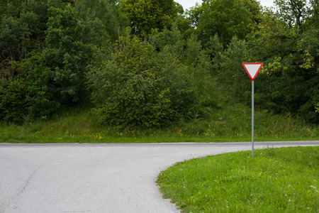Give way traffic sign on a suburban road beside a forestの写真素材