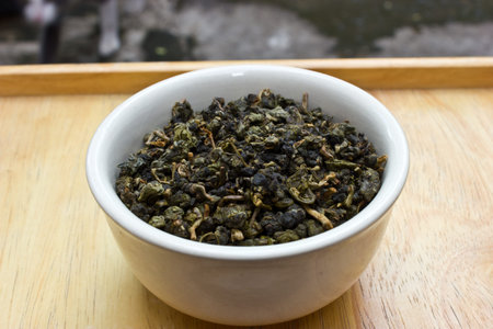 Green leaf tea in bowl on wooden background