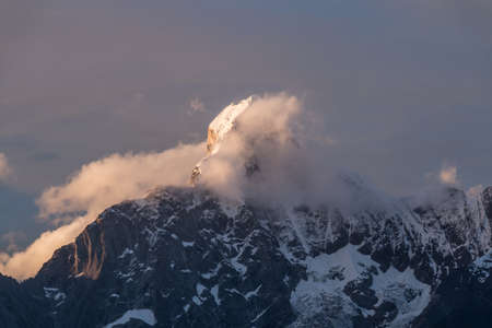 One of the holy mountains in Tibet,covered with snow,with floating clouds around in sunset light.の写真素材