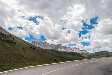 A road as foreground when a rocky mountain in a long distance.の写真素材