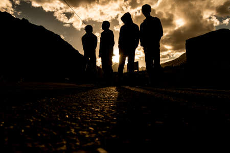 Four people stand on the road during the sunset time.の写真素材