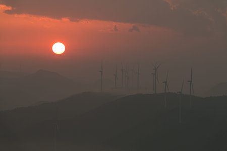 The sunset below clouds with a lot of wind-mill generators on mountains.