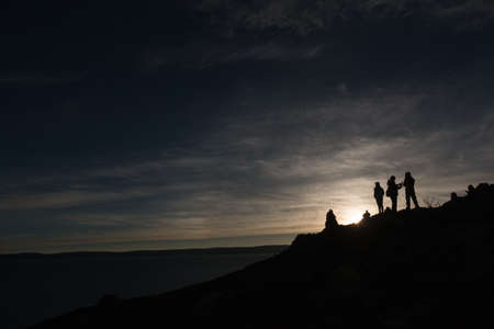A moment of the sunrise of Namtso Lake,silhouette of people standing on slope of a mountain beside the lake,just like standing on the horizon,in the morning in Tibet,China.の写真素材