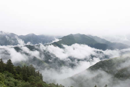 Mountains covered with big blocks of clouds and fogs.の写真素材