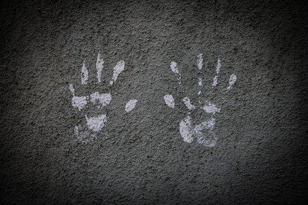 White hand prints on a cement wall with a dark vignette border