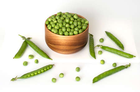 Bowl of green peas and some pods against a white isolated backgroundの写真素材