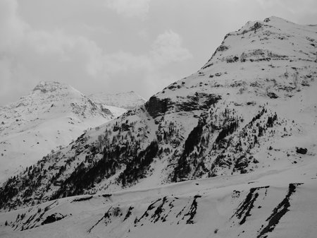 Black and white photo of mountain tops covered with snow having a desolate atmosphere