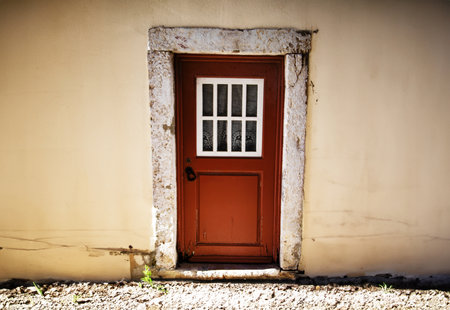 Old wooden door with a white window on a wall in the background in Tagus Port Belem Lisbonの写真素材