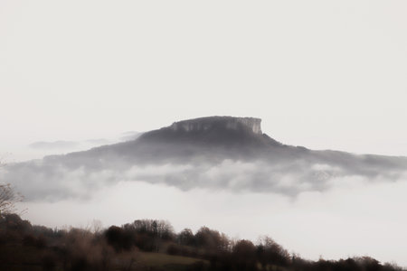 A view of the top of a hill in a foggy day. Mountain landscape in winter. The breathtaking beauty of the Tuscan-Emilian Apennine hills with Bismantova Rock in the distanceの写真素材