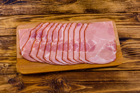 Slices of bacon on cutting board on rustic wooden tableの写真素材