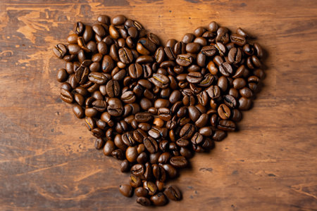 coffee beans in the shape of a heart on a wooden backgroundの写真素材