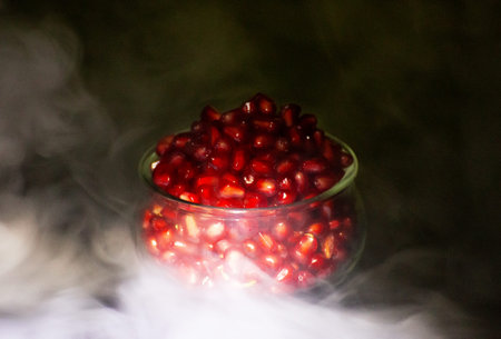 pomegranate seeds in a glass bowl on a dark backgroundの写真素材