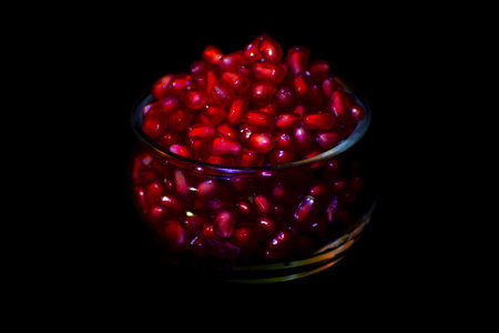Pomegranate seeds in a glass bowl on a black backgroundの写真素材