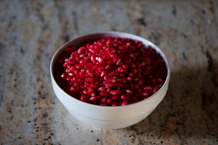 Pomegranate seeds in a bowl on a stone background.の写真素材
