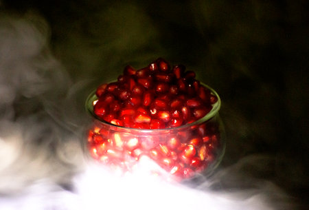 Pomegranate seeds in a glass bowl on a dark backgroundの写真素材