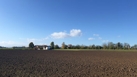 Countryside landscape with farm house and plowed field under blue skyの写真素材