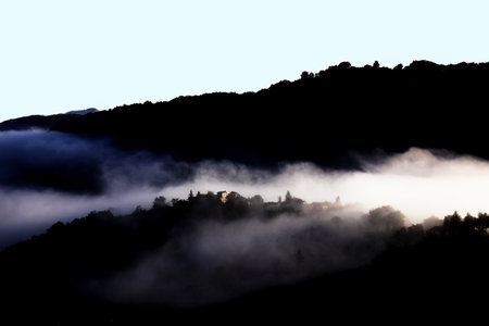 Silhouette of a village in the mountains covered with fog.の写真素材