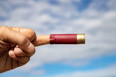 bullet in hand with blue sky and white clouds in the background