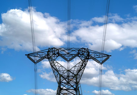 High power pylons against the blue sky with white clouds.の写真素材