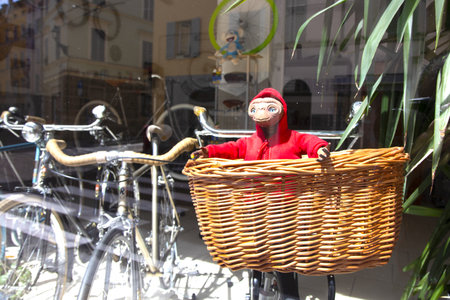 The girl in a red coat and a mask on her face holds a basket with a bicycle.の写真素材