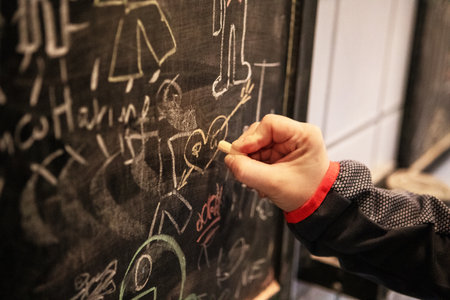 Male hand writing on a blackboard with chalk, education concept.の写真素材