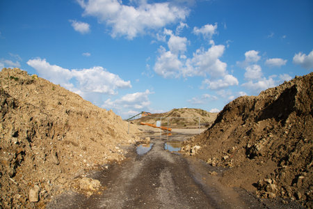 Dirt road in a quarry with blue sky and white clouds.の写真素材