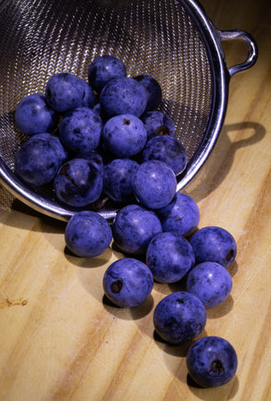Blueberries in a strainer on a wooden table. Toned.