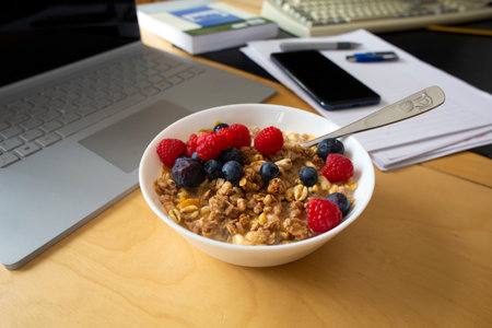 A bowl of cereal with fruit on a teacher's desk before an online lessonのeditorial素材