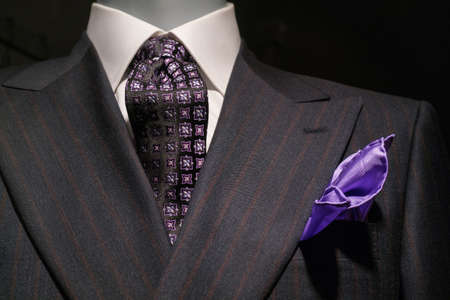 Close up of a dark gray striped jacked with white shirt, patterned black   purple tie and purple handkerchief の写真素材