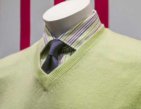 Close-up of a light green v-neck sweater with striped shirt and blue tie 